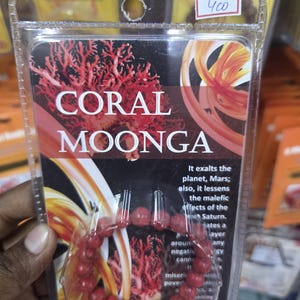 May include: A package containing a red coral bead bracelet. The package has the words "CORAL MOONGA" in large white letters. The package also has a price tag with the number "400" on it.