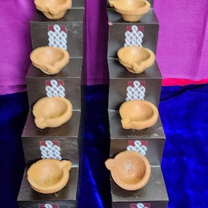 May include: Two sets of decorative, tiered candle holders. Each tier is a dark brown block with a white and red design. Each block holds a small, light brown, bowl-shaped candle holder.