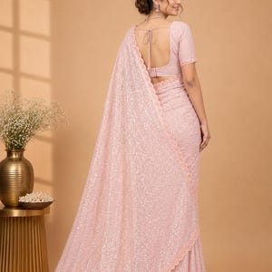 Elegant Indian saree in pastel orange with delicate shimmer work and flowy drape