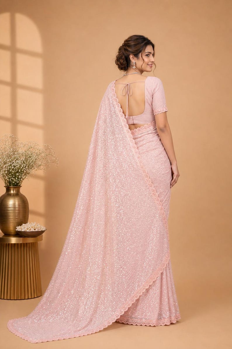 Elegant Indian saree in pastel orange with delicate shimmer work and flowy drape