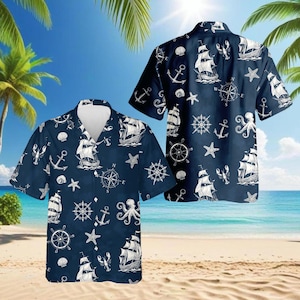 May include: Navy blue short-sleeve shirt with a nautical pattern. The design includes white sailboats, anchors, compasses, starfish, and seashells. The shirt has a button-down front and a relaxed fit, perfect for a day at the beach.