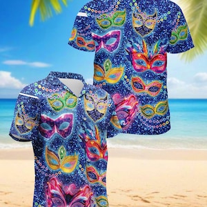 May include: Blue short-sleeved button-down shirt featuring a repeating pattern of colorful masquerade masks. The masks are in various colors, including green, pink, yellow, and red, with glittery accents. The shirt is displayed on a beach background.