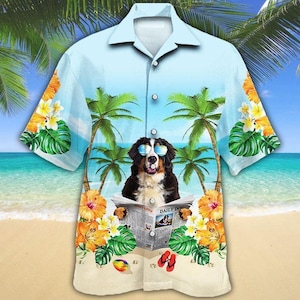 May include: Light blue Hawaiian shirt featuring a dog wearing sunglasses and reading a newspaper on a beach. The shirt has a tropical design with palm trees, flowers, and a beach scene. The newspaper reads "Daily Dog".