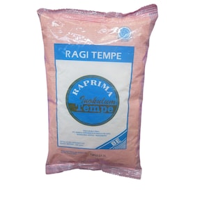 Könnte beinhalten: Ein rosa Beutel mit Ragi Tempe, einem Tempeh-Starter. Der Beutel hat ein blau-weißes Etikett mit dem Text "Ragi Tempe" und "Raprima Inokulum Tempe". Der Beutel ist versiegelt und hat ein kleines kreisförmiges Logo.