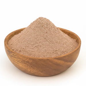 May include: A wooden bowl containing a pile of light brown powder. The bowl has a natural wood grain and sits against a white backdrop. The powder looks finely ground and is evenly distributed throughout the bowl.