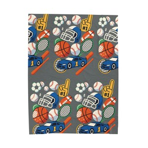 May include: A grey fabric featuring a repeating pattern of sports equipment. The design includes football helmets, basketballs, baseballs, soccer balls, tennis rackets, foam fingers, and blue race cars. The sports-themed pattern is suitable for various products.