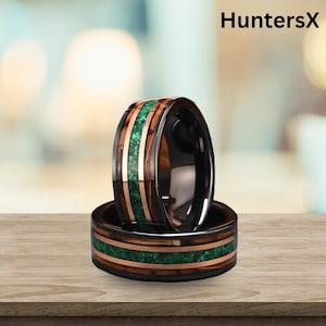May include: Two black rings with a wood grain and green stone inlay. The rings have a copper-coloured band and are stacked on top of each other. The text "HuntersX" is in the top right corner.