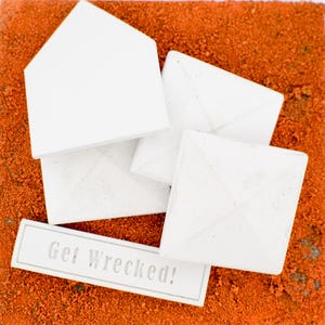 May include: White baseball bases and home plate on an orange, textured surface. A sign with the text "Get Wrecked!" is visible. The bases are square and diamond-shaped. The image uses imperial measurements.