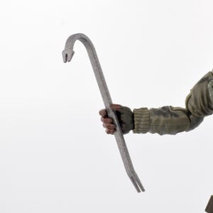 Puede incluir: Una palanca de metal gris con un extremo curvado y una punta bifurcada es sostenida por una figura que lleva una chaqueta de estilo militar verde y marrón. La palanca es el foco principal sobre un fondo blanco.