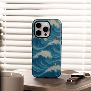 以下が含まれることがあります： 青と白の波の絵が描かれた携帯電話ケース。3つの小さなヨットが描かれています。ケースは黒い縁取りとカメラ用の切り抜きがあります。