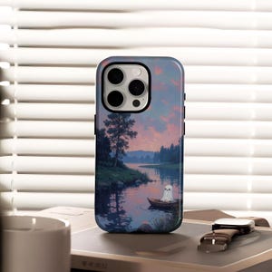 May include: A phone case featuring a serene landscape painting with a ghost in a boat on a lake. The artwork includes a sunset with pink and purple hues, trees, and water. The case has a black border.