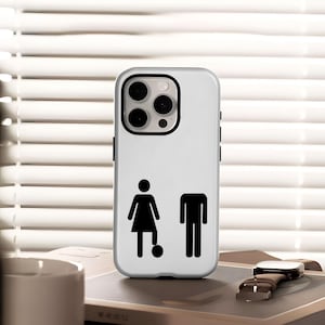 Pode incluir: Capa de smartphone branca com um gráfico a preto e branco de um boneco a jogar futebol e um boneco sem cabeça. A capa tem uma moldura preta para a lente da câmara e botões laterais pretos.