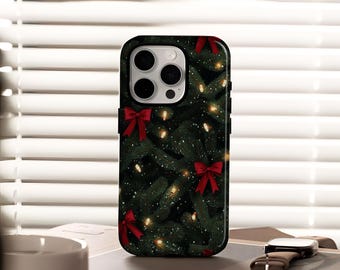 Puede incluir: Funda de teléfono inteligente negra con un diseño de árbol de Navidad. La funda tiene un fondo verde oscuro con lazos rojos, luces de cadena y un poco de nieve. La funda del teléfono está sobre una mesa con un reloj y una taza de café.