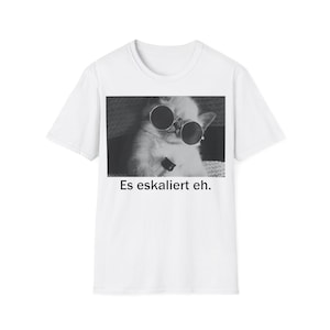 May include: White t-shirt featuring a black and white image of a cat wearing sunglasses. The image includes the text "Es eskaliert eh."