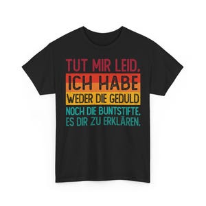May include: Black t-shirt with a retro design. The text in the design reads "TUT MIR LEID. ICH HABE WEDER DIE GEDULD NOCH DIE BUNTSTIFTE, ES DIR ZU ERKLÄREN." The text is in a retro color scheme of red, orange, yellow, and teal.