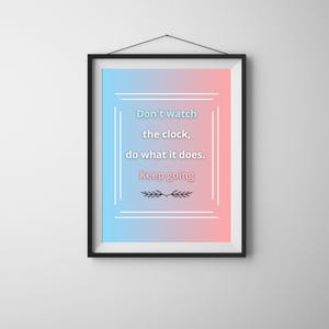 May include: Framed wall art with a gradient background of blue and pink. The artwork features the text "Don't watch the clock, do what it does. Keep going" in a white frame. A decorative sprig is at the bottom.