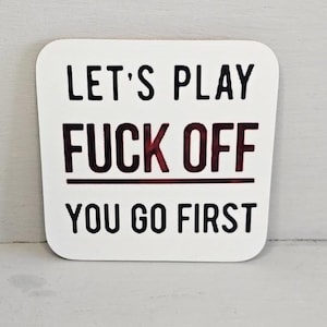Puede incluir: Posavasos cuadrado blanco con esquinas redondeadas. El posavasos tiene texto negro que dice "LET'S PLAY FUCK OFF YOU GO FIRST" con la palabra "FUCK" en color rojo oscuro.