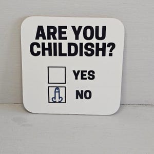 Op de afbeelding: Witte vierkante sticker met afgeronde hoeken. Vetgedrukte zwarte tekst luidt "ARE YOU CHILDISH?" met een selectievakje naast "YES" en een afbeelding van een penis naast "NO".