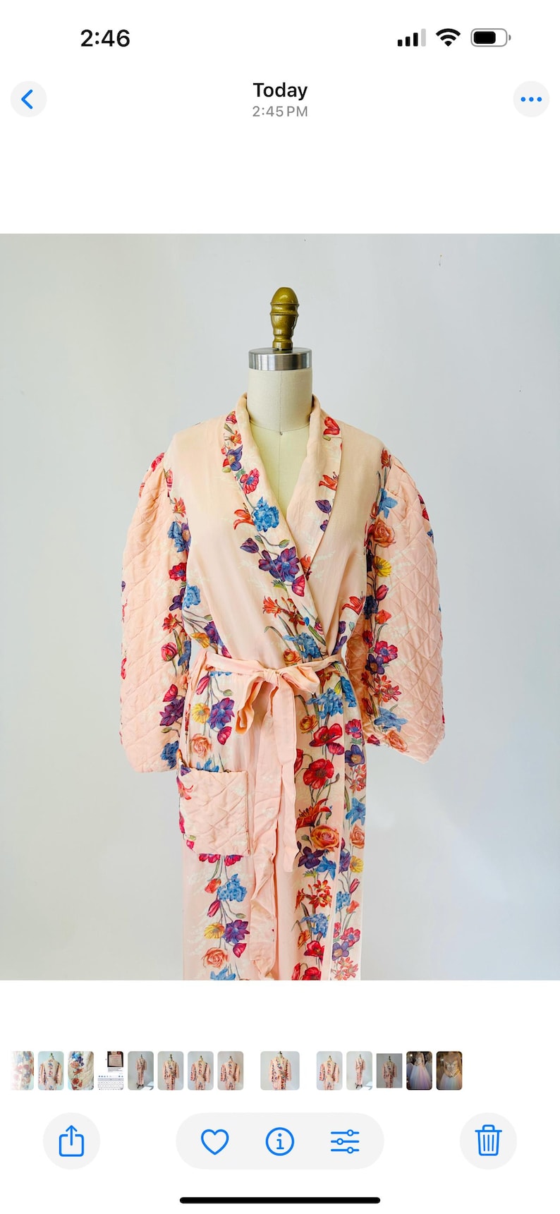 May include: A peach-colored robe with a floral pattern of blue, red, and purple flowers. The robe has quilted sleeves and a matching belt. The robe is displayed on a mannequin.