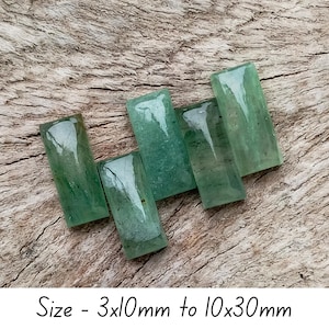 May include: Five rectangular, translucent green gemstones are displayed on a wooden surface. The gemstones vary in size, with dimensions ranging from 3x10mm to 10x30mm. The text "Size - 3x10mm to 10x30mm" is displayed below the gemstones.
