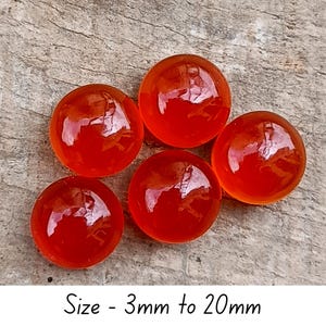 May include: Five translucent, round, orange-red glass beads. The beads have a glossy finish and reflect light. Text at the bottom reads "Size - 3mm to 20mm".