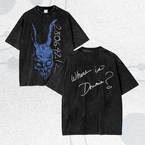 Può includere: T-shirt nero dall'aspetto invecchiato, con un disegno di teschio di coniglio blu e la scritta "28:06:42:12". Sul retro della maglietta compare la frase scritta a mano "Where is Donnie?" Un capo d'abbigliamento unico.