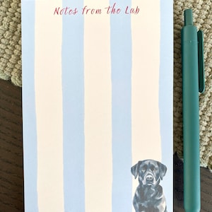 May include: A notepad with blue and white vertical stripes and the text "Notes from the Lab" in burgundy. A watercolor illustration of a black Labrador Retriever is at the bottom. A teal pen is to the right.