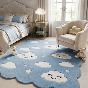May include: A large, cloud-shaped area rug in light blue, featuring white clouds with smiling faces, pink cheeks, and closed eyes, interspersed with small white stars. The rug has a scalloped edge and a soft, textured pile surface.