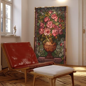 May include: A stained glass panel featuring a vase overflowing with pink roses, set in a gold frame. A red leather chair and a wooden ottoman with a white cushion are in the foreground. The room has a hardwood floor and natural light.