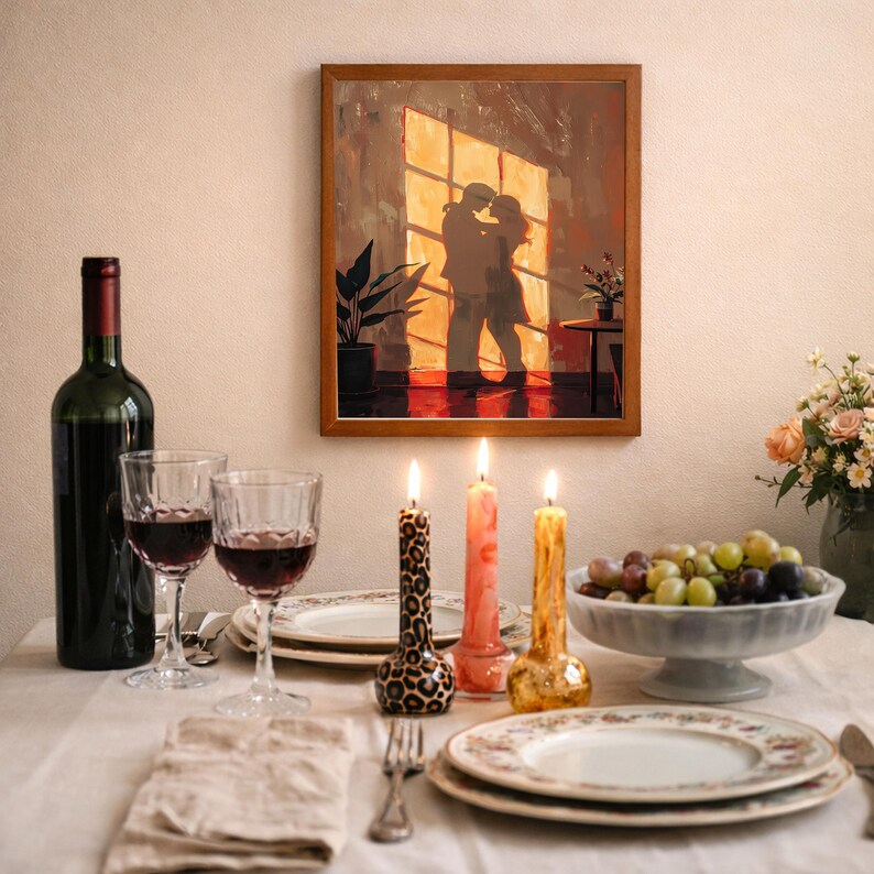 May include: A romantic dinner setting with a framed painting of a couple, candles, wine glasses, and a bottle of wine. A bowl of grapes and a vase of flowers complete the scene. The table is set with plates and silverware.