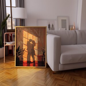 May include: A framed artwork depicts a couple embracing in front of a window, bathed in warm sunlight. The painting features a palette of browns, oranges, and reds, with a gold frame. The artwork is displayed in a living room setting with a sofa and plants.