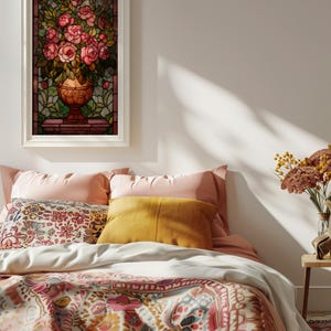 May include: A framed stained glass artwork featuring a bouquet of pink roses in a bronze vase. The artwork is set against a backdrop of green and brown stained glass. The image is displayed above a bed with pink and patterned bedding.