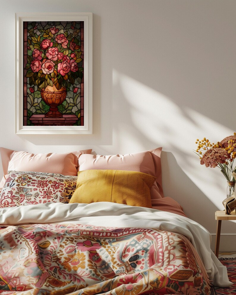 May include: A framed stained glass artwork featuring a bouquet of pink roses in a bronze vase. The artwork is set against a backdrop of green and brown stained glass. The image is displayed above a bed with pink and patterned bedding.