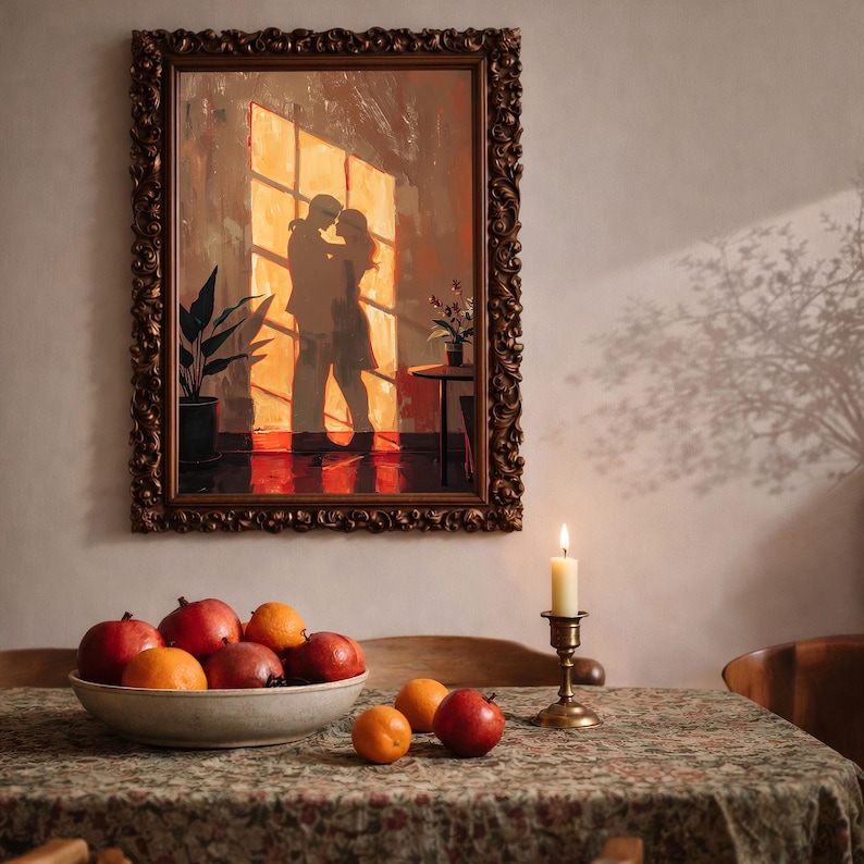 May include: A framed artwork depicts a couple embracing in front of a sunlit window. The painting is in a gold ornate frame. A bowl of fruit and a lit candle sit on a table covered with a floral tablecloth. The scene evokes warmth and intimacy.