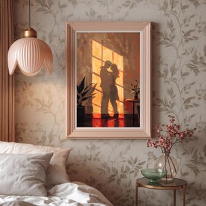 May include: A framed artwork depicts a couple embracing in front of a sunlit window. The painting features warm tones of orange and brown, with a soft pink frame. A potted plant and small table with flowers are visible.