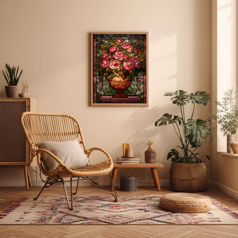May include: A framed stained glass artwork featuring a bouquet of pink roses in a decorative vase. The artwork is set against a backdrop of green and brown glass. The scene is in a room with a wicker chair, rug, and plants.