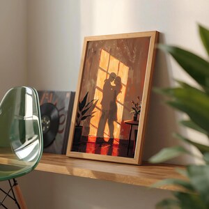 May include: A framed art print depicts a couple embracing in front of a sunlit window. The artwork features warm tones of orange, brown, and red, with a wooden frame. The scene includes potted plants and a small table, creating a cozy atmosphere.
