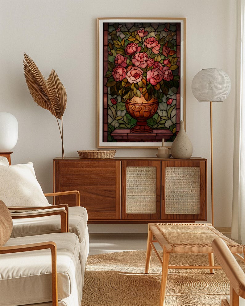 May include: A framed stained glass art piece featuring a bouquet of pink roses in a decorative vase. The artwork is set against a backdrop of green and brown stained glass, with a wooden frame. The image is displayed in a well-lit living room setting.