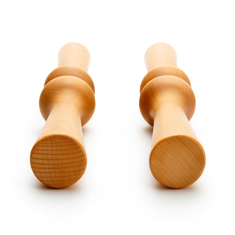 Pode incluir: Dois rolos de massagem de madeira clara. Cada rolo tem uma pega cil&iacute;ndrica, uma extremidade arredondada e duas sec&ccedil;&otilde;es esf&eacute;ricas. Projetados para terapia muscular e relaxamento, medem cerca de 20 cm de comprimento.