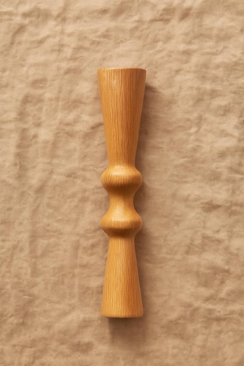 Pode incluir: Um casti&ccedil;al de madeira clara com uma forma de ampulheta &uacute;nica. O casti&ccedil;al apresenta uma base e uma parte superior alargadas, com uma sec&ccedil;&atilde;o arredondada e bulbosa no meio. O gr&atilde;o da madeira &eacute; vis&iacute;vel, adicionando textura ao design.