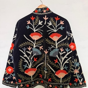 Pu&ograve; includere: Una giacca nera con intricati ricami floreali nelle tonalit&agrave; del rosso, rosa, blu e verde. Il design presenta fiori stilizzati e motivi a fogliame sul retro e sulle maniche, con un bordo decorativo lungo l'orlo e il colletto.