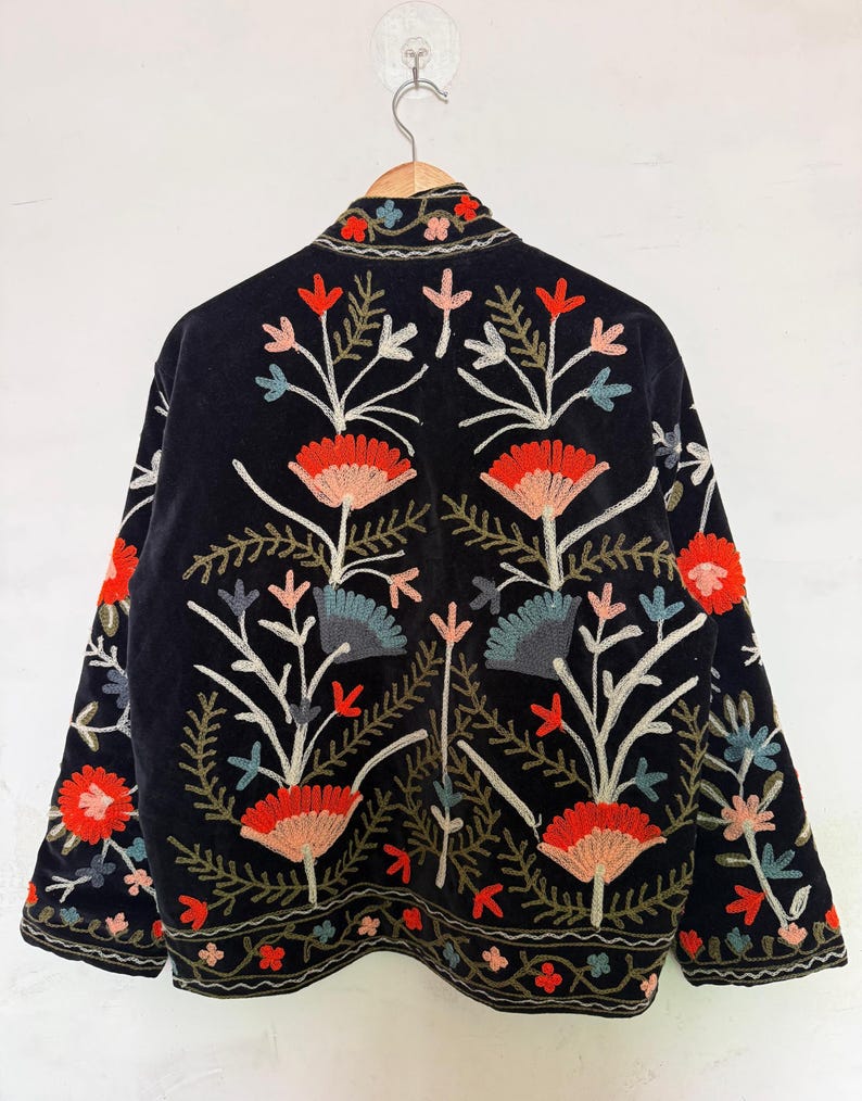 Pu&ograve; includere: Una giacca nera con intricati ricami floreali nelle tonalit&agrave; del rosso, rosa, blu e verde. Il design presenta fiori stilizzati e motivi a fogliame sul retro e sulle maniche, con un bordo decorativo lungo l'orlo e il colletto.