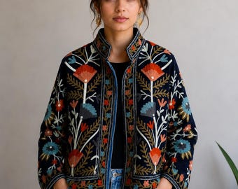 May include: A dark navy blue jacket featuring a high collar and long sleeves, adorned with intricate multi-colored floral embroidery in shades of red, light blue, and white. The garment has a straight hem and an open front design.