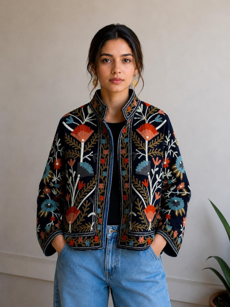 Pu&ograve; includere: Una giacca blu navy scuro con colletto alto e maniche lunghe, decorata con intricati ricami floreali multicolori nelle tonalit&agrave; del rosso, azzurro e bianco. Il capo presenta un orlo dritto e un design aperto sul davanti.