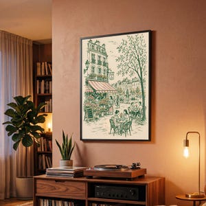 Puede incluir: Una l&aacute;mina de arte enmarcada con un dibujo lineal detallado de una escena callejera parisina con un caf&eacute;, una florister&iacute;a y personas sentadas en mesas al aire libre. La ilustraci&oacute;n utiliza tinta verde sobre un fondo crema.