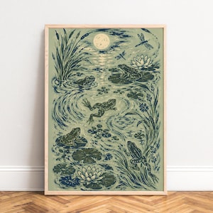 Peut inclure: Une impression d'art encadrée représentant une scène d'étang avec des grenouilles vert foncé, des nénuphars et des fleurs blanches. L'illustration comprend des roseaux, des libellules et une pleine lune sur un fond vert sauge atténué.