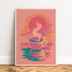 Peut inclure: Une impression d'art rectangulaire dans un cadre en bois clair représentant une illustration stylisée d'une tasse de café posée sur l'eau. La scène montre un grand soleil rose, des nuages orange et une tasse fumante avec un croissant de lune.