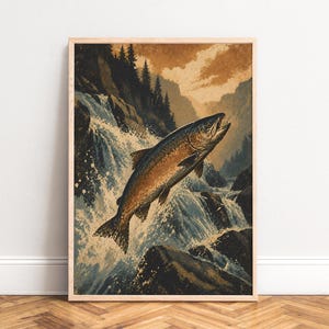 May include: A framed vertical art print featuring a brown salmon leaping upward through a rushing waterfall. The scene includes dark rocky cliffs, evergreen trees, and a warm, golden-toned sky in the background, all enclosed in a light wood frame.