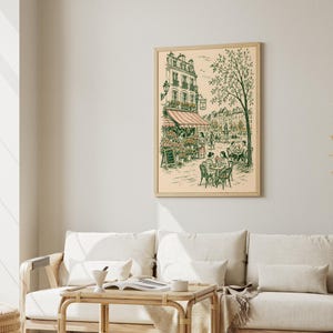 Puede incluir: Una l&aacute;mina de arte enmarcada con un dibujo lineal detallado de una escena callejera parisina. La ilustraci&oacute;n muestra un caf&eacute; con mesas al aire libre, una florister&iacute;a con un toldo a rayas y un &aacute;rbol alto, en tonos verdes y rosados.