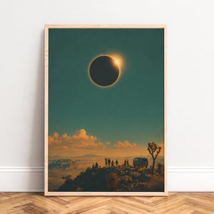 Può includere: Una stampa artistica da parete verticale incorniciata che raffigura un'eclissi solare in un cielo blu ottanio scuro sopra un paesaggio desertico. Sagome di un gruppo di persone e un furgone su una scogliera sotto nuvole dorate, con un albero di Giosuè.
